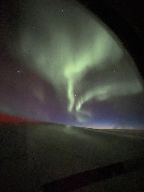 Zelená polární záře viditelná z okna letadla