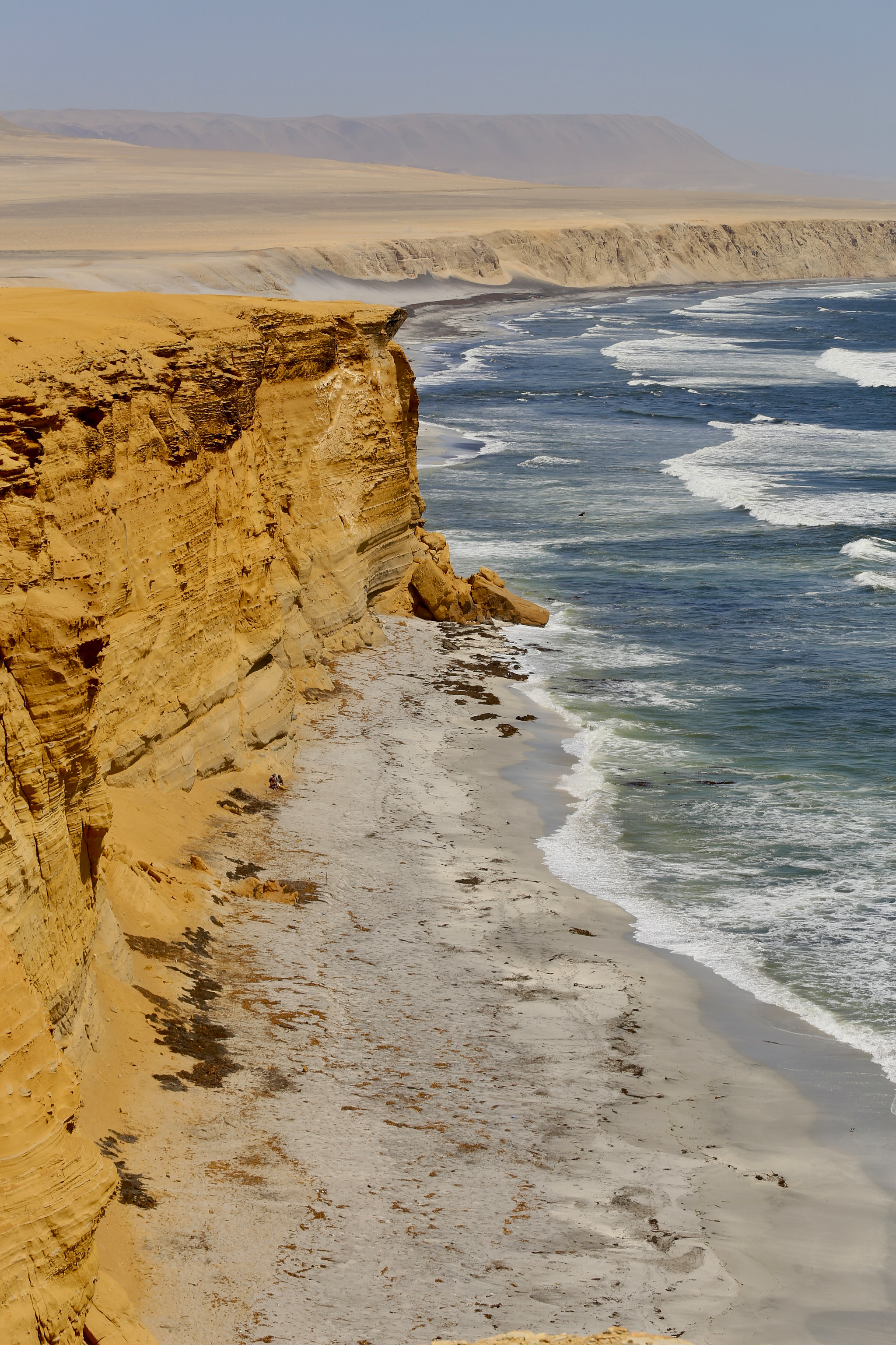 Žluté útesy nad bouřlivým oceánem v Paracas