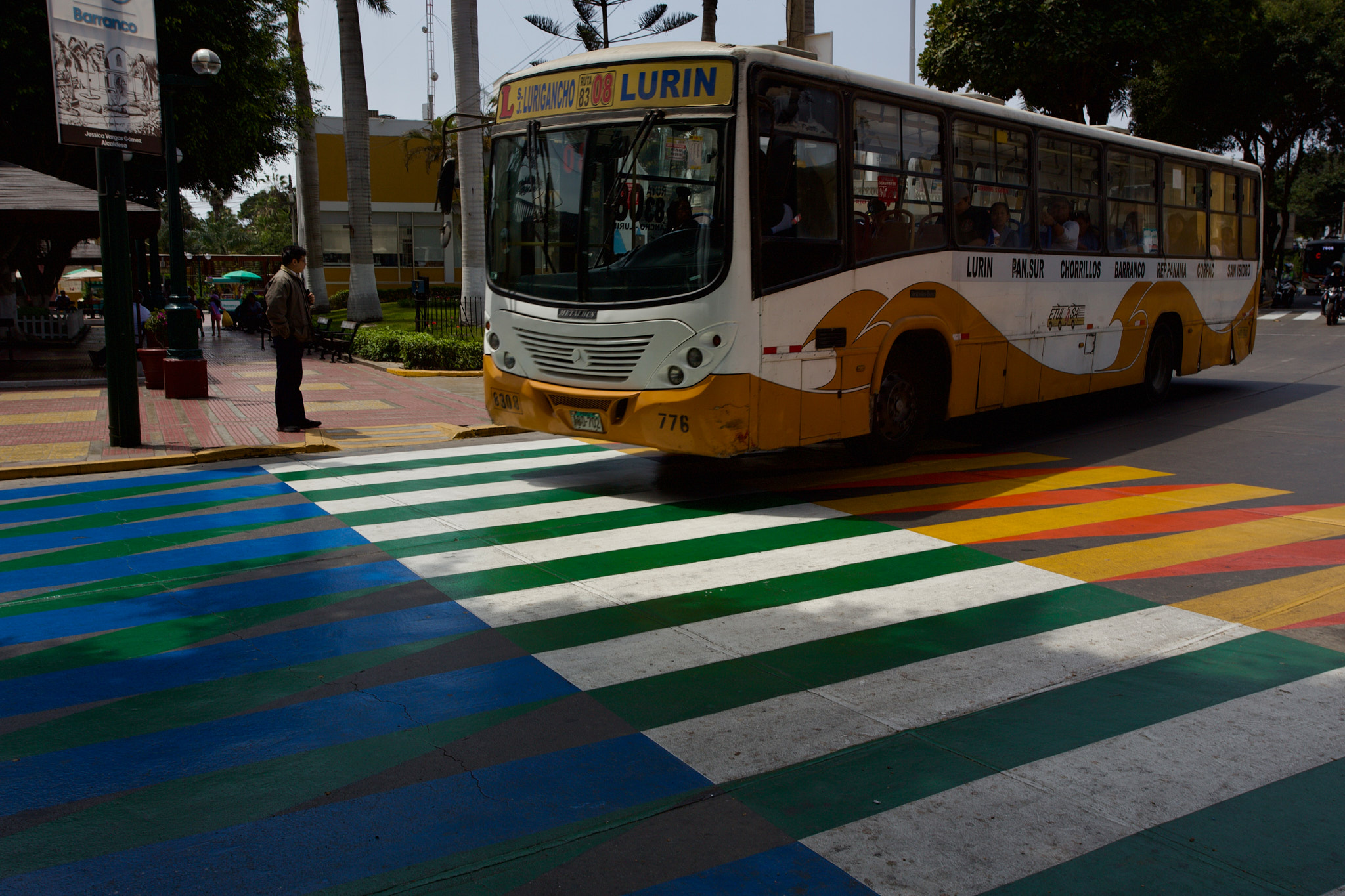 Žlutý autobus přejíždí přes duhově zbarvený přechod pro chodce v centru Limy