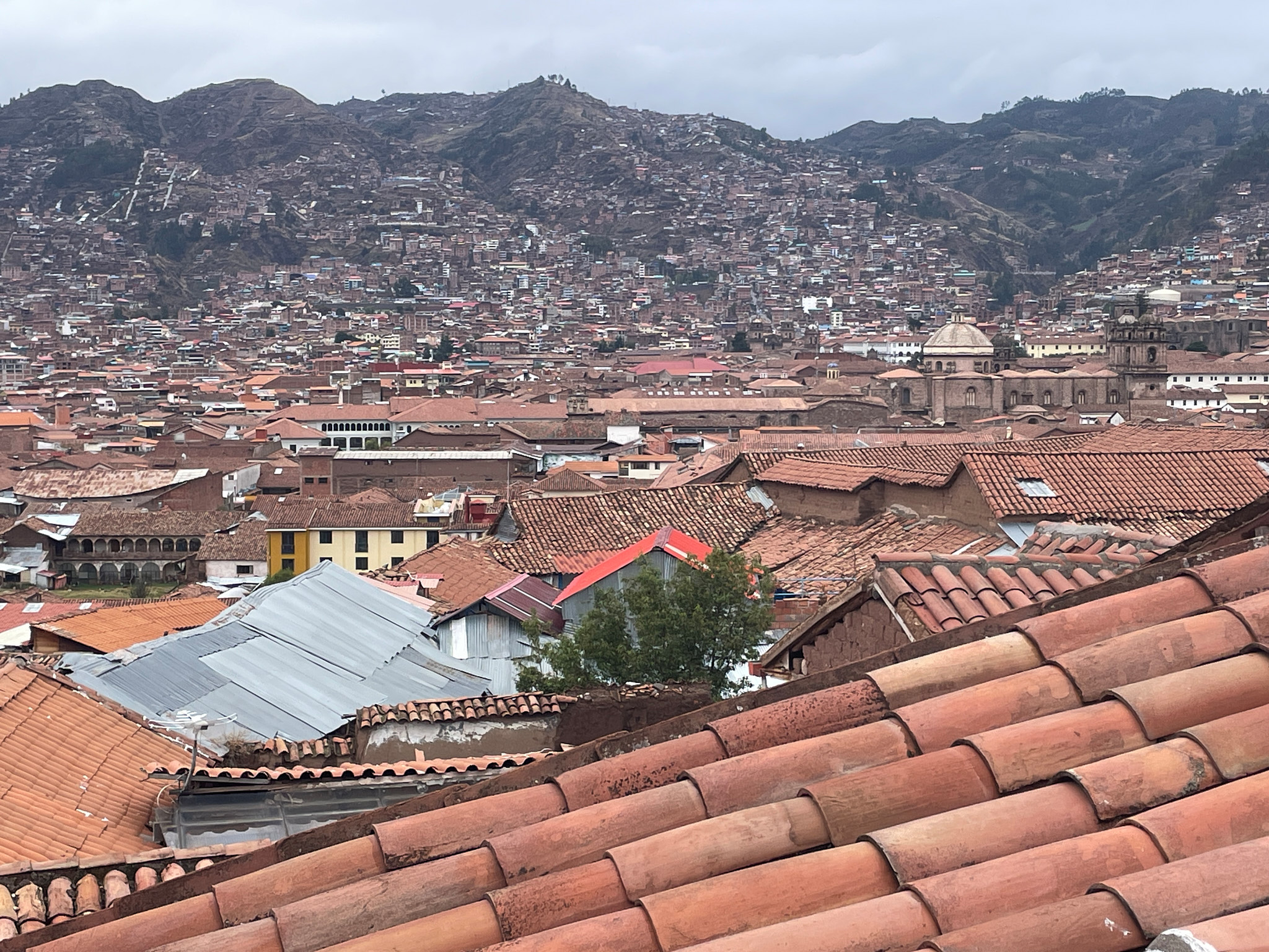 Panoramatický pohled na Cusco ze střechy hotelu s terakotovými střechami a kopci