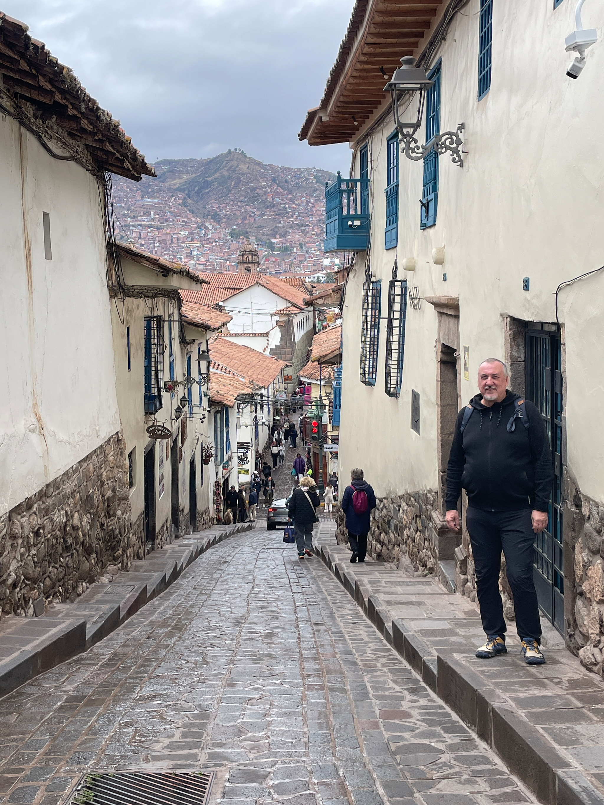Petr prochází úzkou uličkou podél incké kamenné zdi s výhledem na Cusco